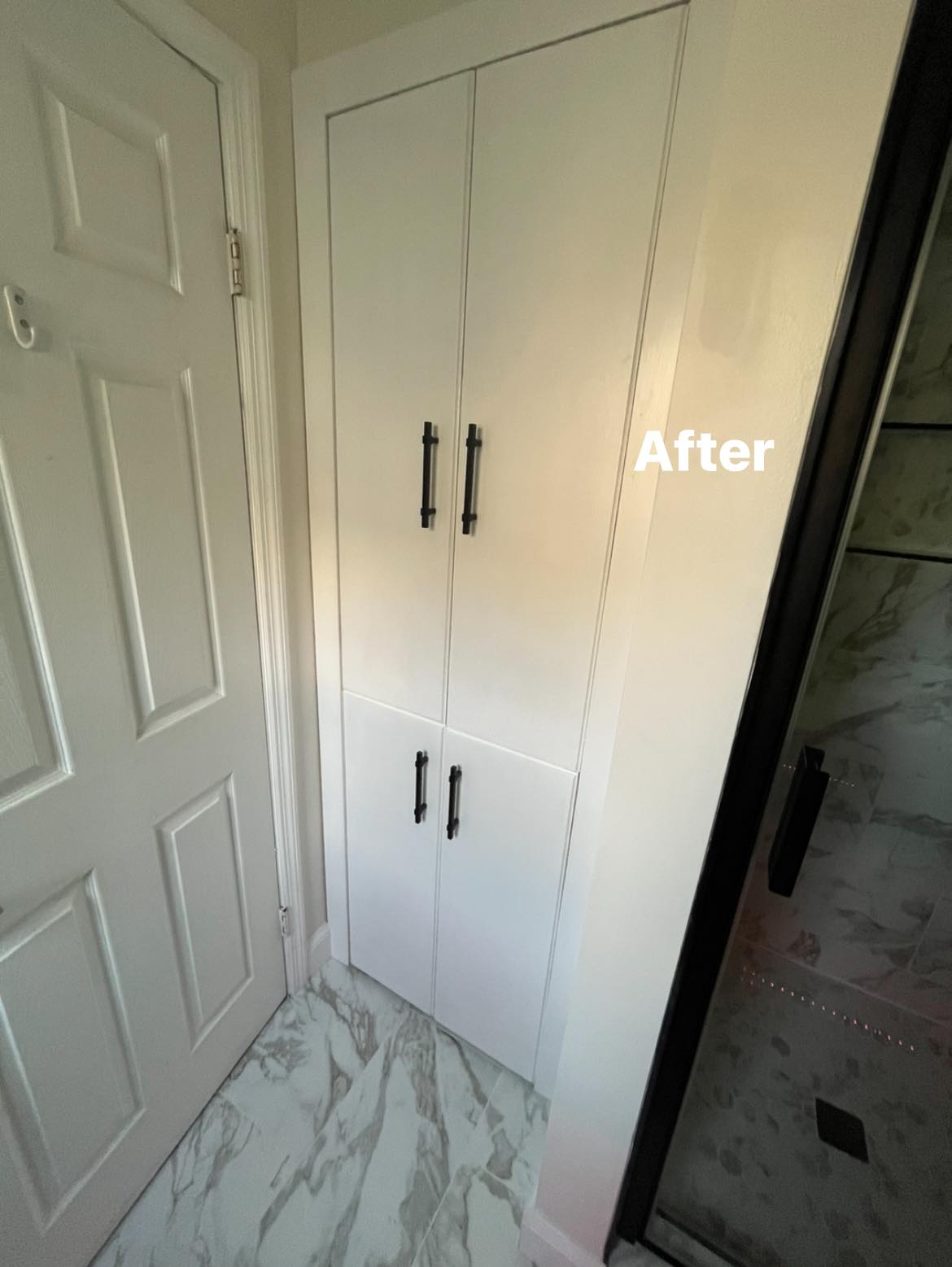 Tall white built-in bathroom cabinet next to a shower enclosure