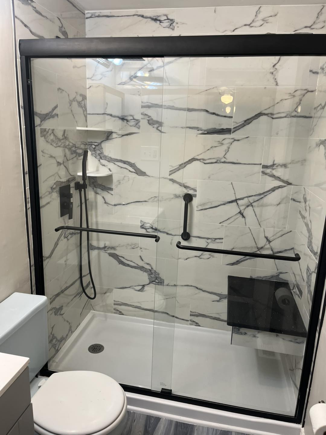 Bathroom shower with black framed glass enclosure and marble-look wall tile